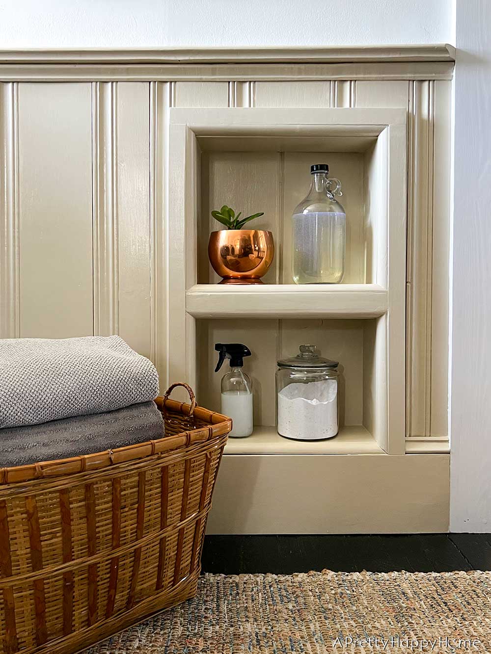 the perk of decanting laundry detergent in a modern country laundry room with inset shelves and wainscoting
