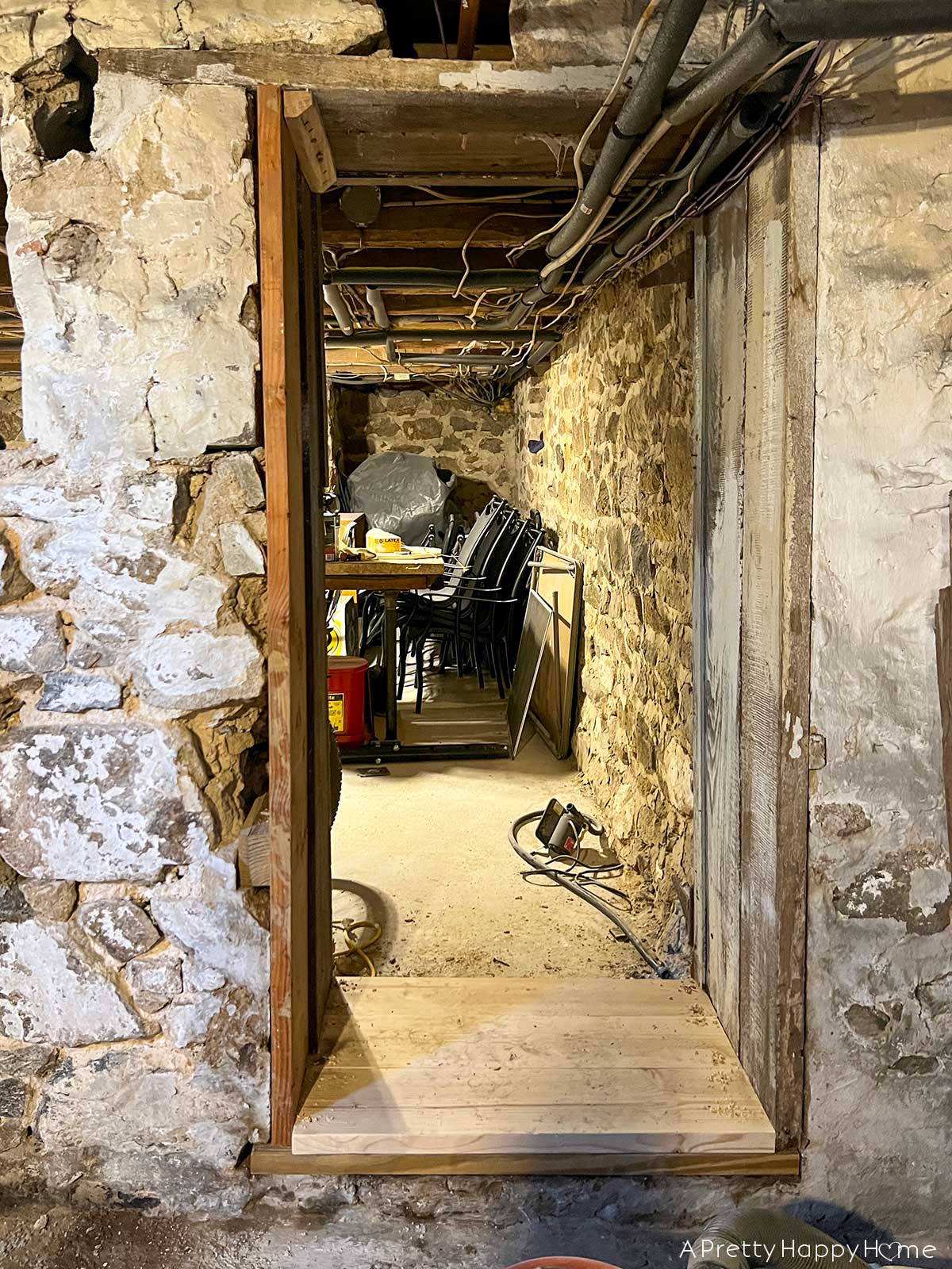 stone foundation in a 1780s home showing a foundation wall in need of repointing and repair and a doorway constructed of planks mortared into the foundation.