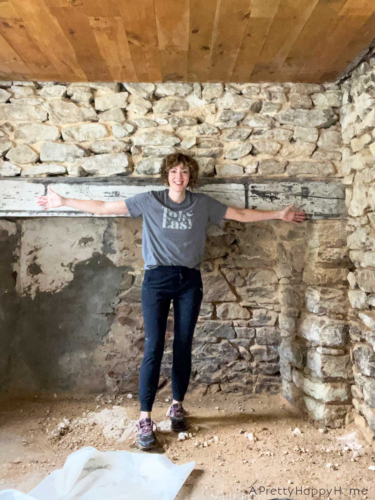 annisa jones repointing stone foundation walls in a carriage house july 2024 while wearing a take it easy shirt
