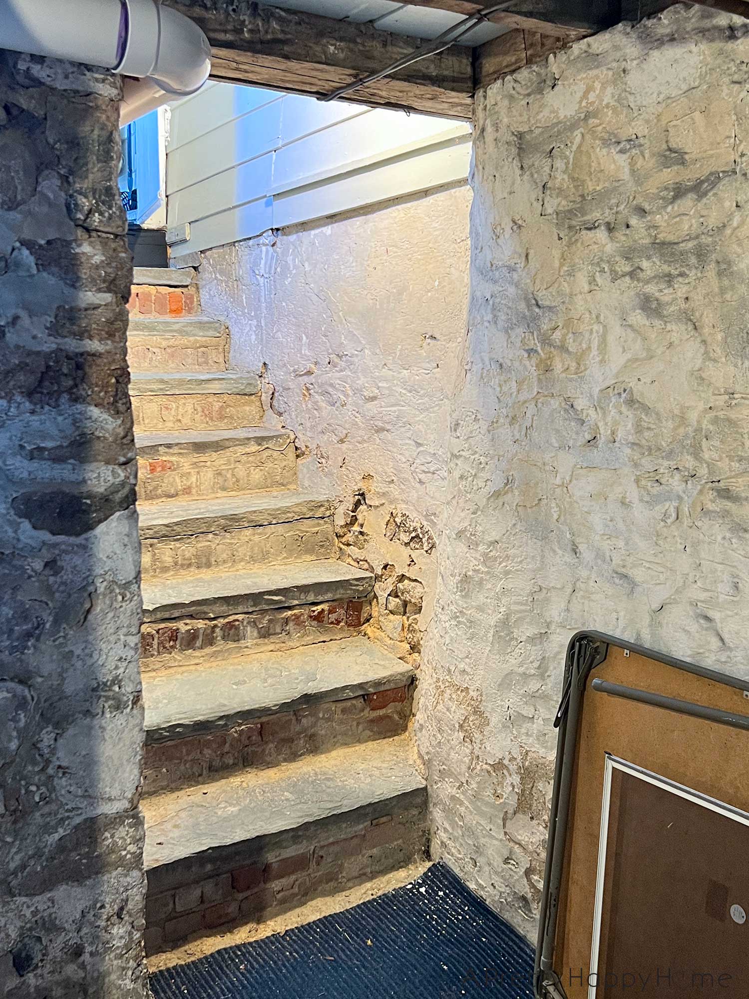 before photo of old flagstone steps down to a basement. the stairwell walls are made of stone. Both the stair risers and the walls need to be repointed with lime mortar.