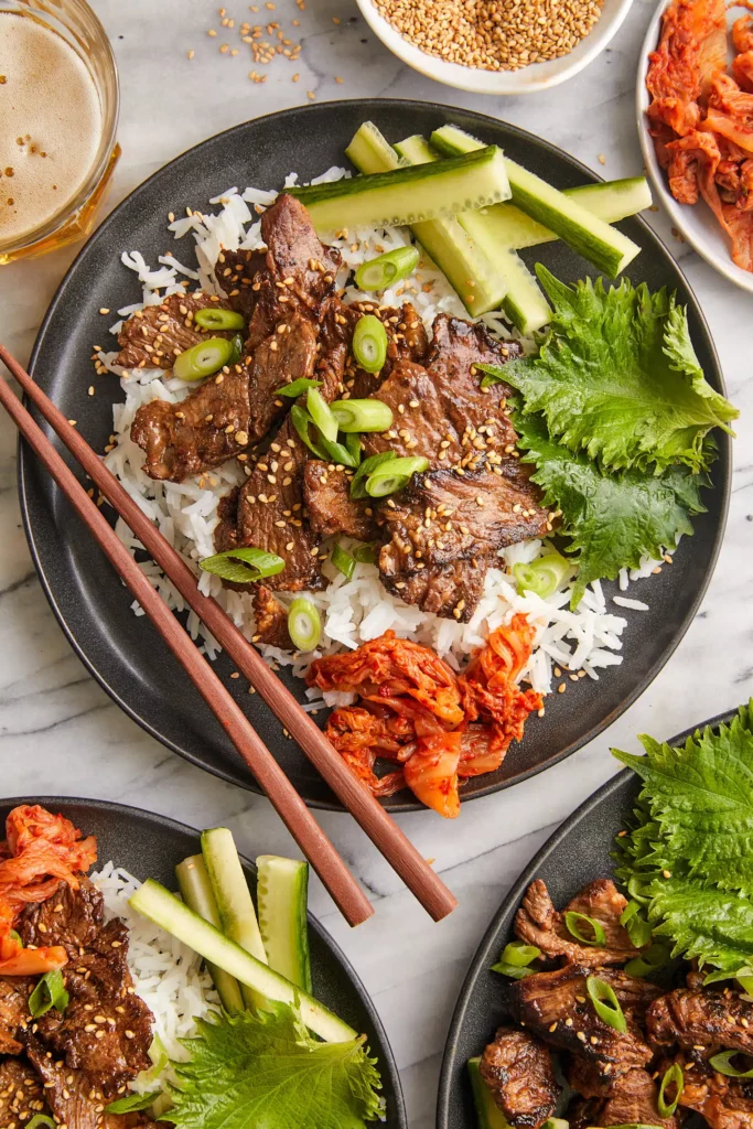 Damn Delicious' Korean Beef Bulgogi show here served on a bed of rice with a side of cucumbers and kimchi.